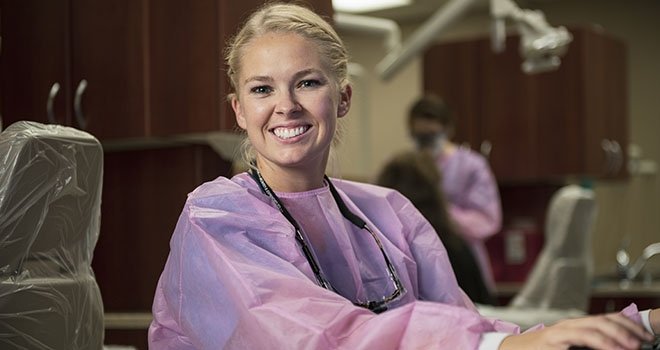 smiling woman in pink scrubs in a dentist office