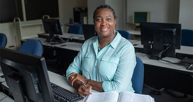 Female TCC Health Information Technology student smiles while studying at computer.