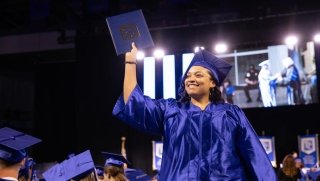A student holds up her degree at the Spring 2024 Commencement ceremony.
