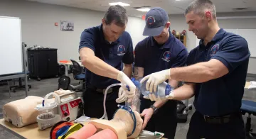 Three students work on a medical manikin