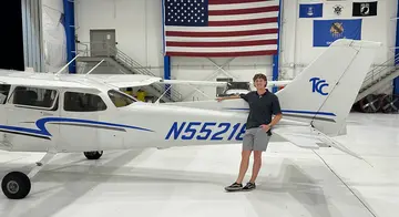 Grant Casebeer stands in front of a plane