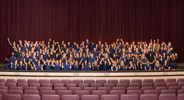 A group picture of a very large group of students on the stage of the VanTrease Performing Arts Center for Education.