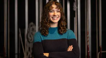 Moriah Jestus smiles at the camera with her arms crossed