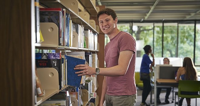 man pulling book off of library shelf