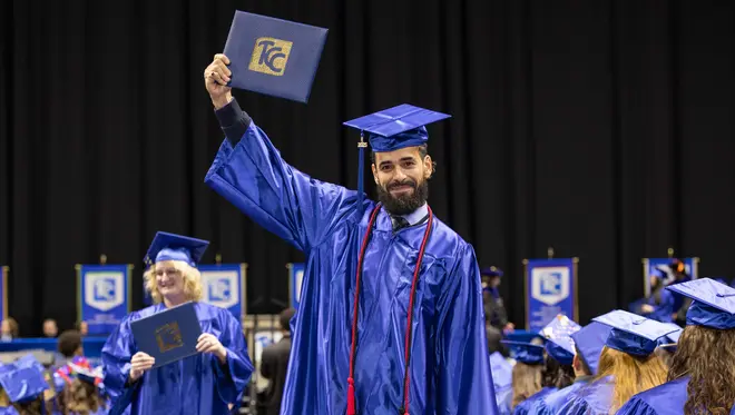 Abraan Lopez hold his degree above his head at commencement.