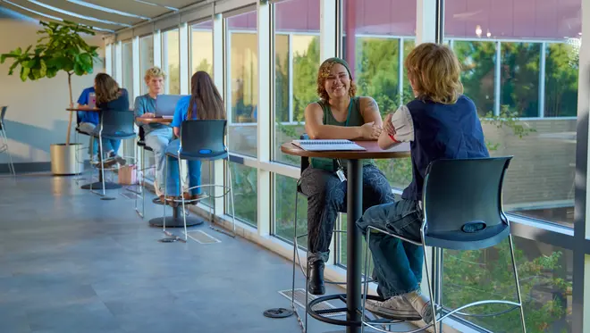 Two students sit at table and converse in TCC's Southeast Campus Student Union.