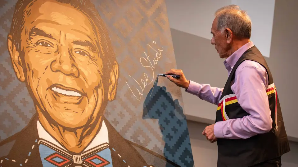 Wes Studi signs a 6-foot-by-5-foot spray-painted portrait of himself.