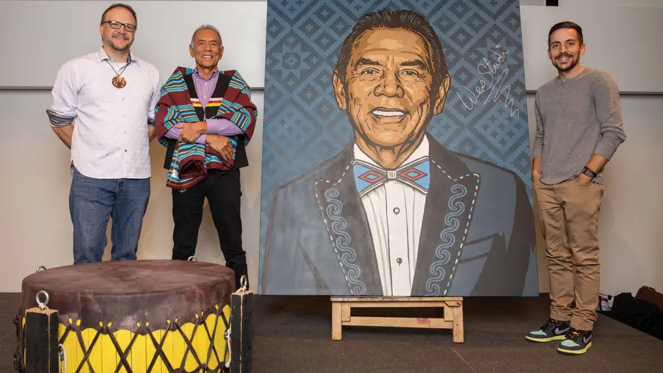 Artist Bryan Waytula, Wes Studi, and artist Nick White stand beside a 6-foot-by-5-foot spray-painted portrait of Studi.