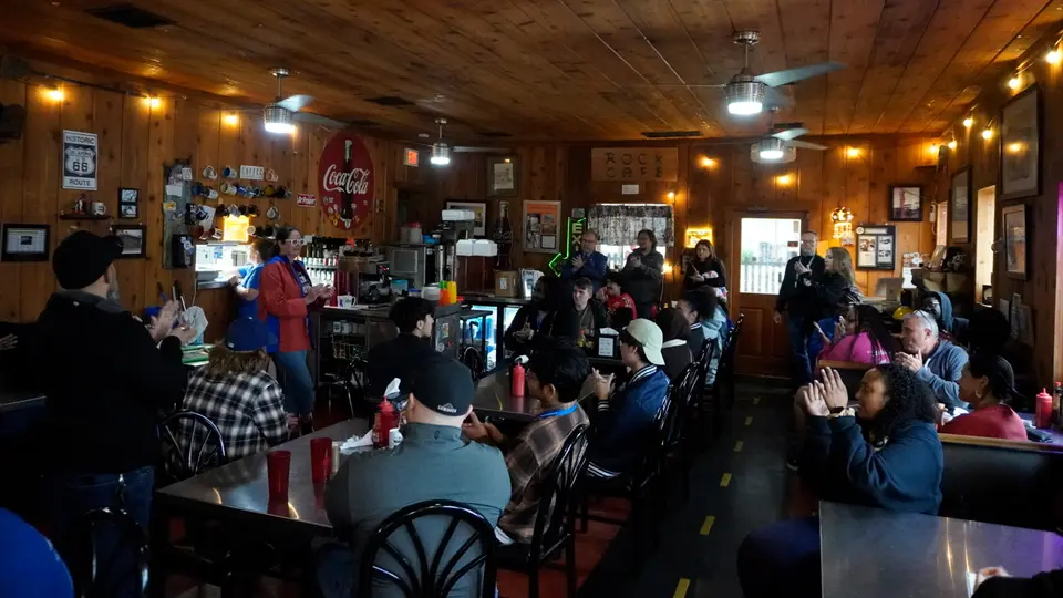 A woman peaks to a group of about 30 people sitting down in chairs at Rock Cafe in Stroud