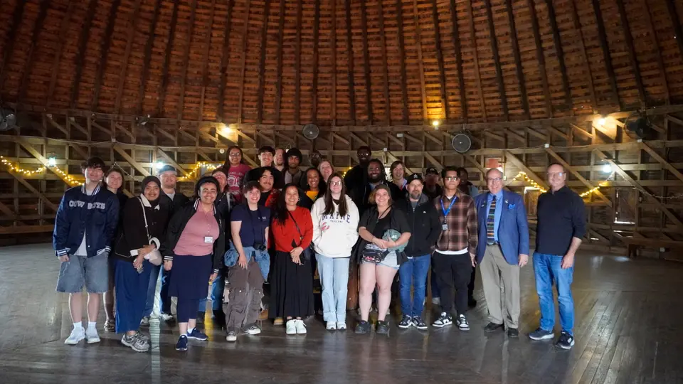 A group of 30 people poses for a photo inside the Round Barn