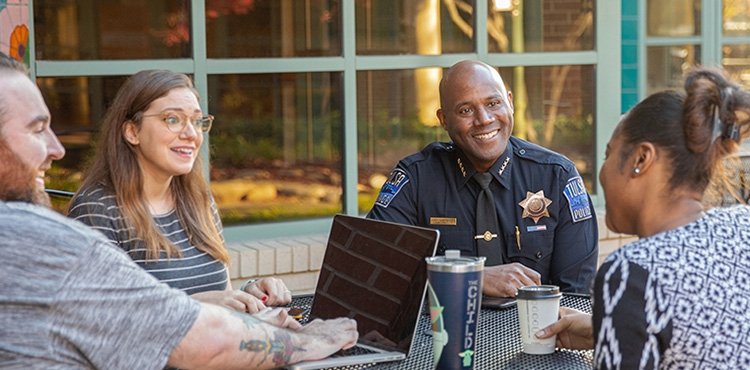 Police officer meets at a table out doors with community members