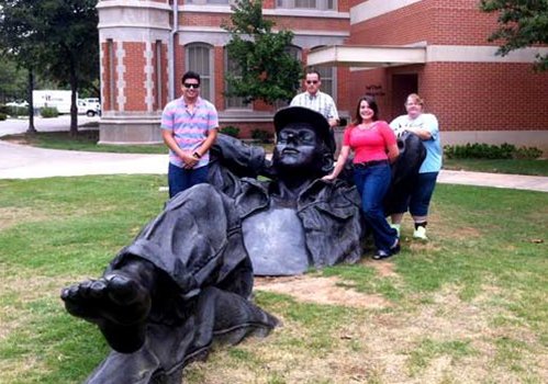 Four TCC TRIO Students stand behind a large stature of a reclining man.