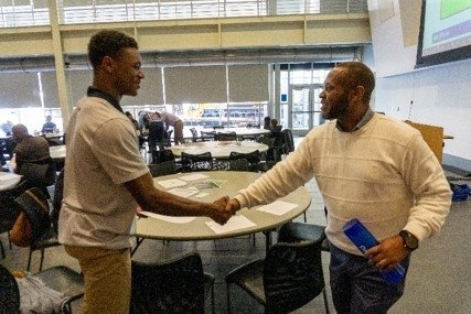 TCC African American male student shaking hands with African American male mentor.