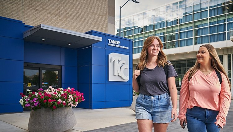 Two young woman walk along the street past the entrance to the TCC Tandy Student Success Center of the downtown, Metro Campus..