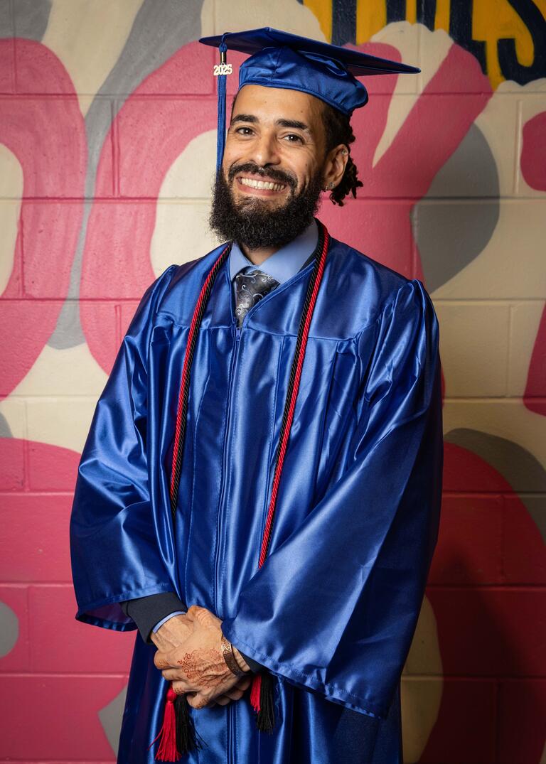 Abraan Lopez is smiling, dressed in blue graduation regalia.